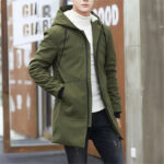 Parka hiver homme coupe vent avec capuche, de couleur kaki, porté par un mannequin debout avec un haut blanc