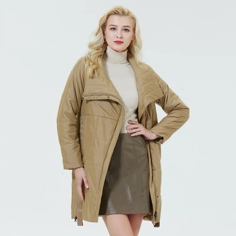 0-6b5f24.jpeg Parka matelassée femme avec col à revers marron, porté par une femme blonde debout, sur fond bleu clair.