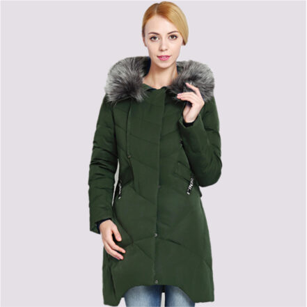 Parka duvet femme avec capuche en fausse fourrure, de couleur verte, portée par une femme. Sur un fond rose clair.