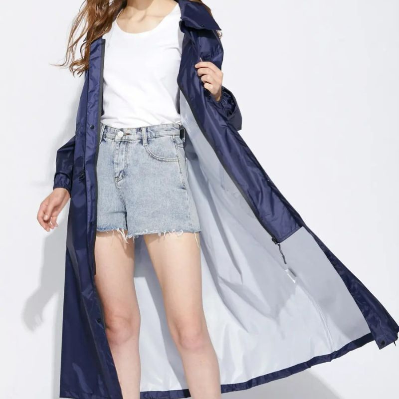 Parka cirée femme imperméable longue et fine Mannequin femme portant un short en jean avec un t-shirt blanc et une parka cirée longue ouverte bleu foncé et gris pâle à l'intérieur.