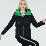 Femme mannequin portant une parka courte noire, fermée. La doublure est verte caire.