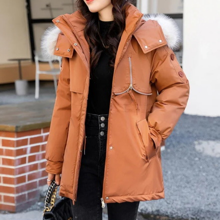 Parka déperlante femme orange avec grand col en fourrure sur une femme sur fond gris