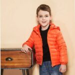 Jeune garçon accoudé sur un bureau portant une parka doudoune enfant.