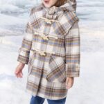 Petite fille portant une parka à carreau, avec une capuche et deux grandes poches plaquées sur l'avant.