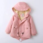 Parka enfant rose clair avec une capuche et des cordons pour ajuster la coupe. Doublure beige épaisse toute douce.