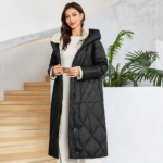 Parka hiver femme noire et matelassée avec ceinture sur une femme sur un fond d'escalier beige et une plante avec murs blancs