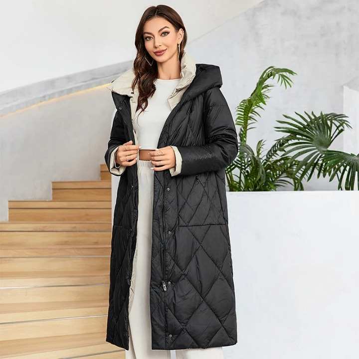 Parka hiver femme noire et matelassée avec ceinture Parka hiver femme noire et matelassée avec ceinture sur une femme sur un fond d'escalier beige et une plante avec murs blancs