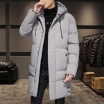 Parka hiver homme effet matelassé gris avec capuche, longue et de couleur grise, portée par un homme