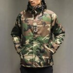 Parka homme imperméable avec capuche de style militaire, porté par un homme avec les mains dans les poches