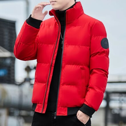 Parka matelassée homme avec col haut et conception épaisse, de couleur rouge portée par un homme debout