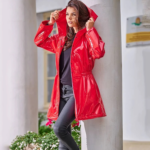 Parka pluie femme imperméable et brillante avec capuche sur une femme posée contre un pilier