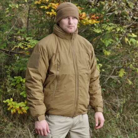 Parka pluie homme style militaire imperméable et épaisse, de couleur marron, porté par un homme debout avec un bonnet assorti