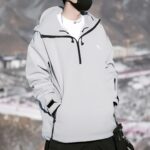 Parka ski grise et coupe-vent sur un homme sur fond de montagnes