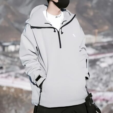 Parka ski grise et coupe-vent sur un homme sur fond de montagnes