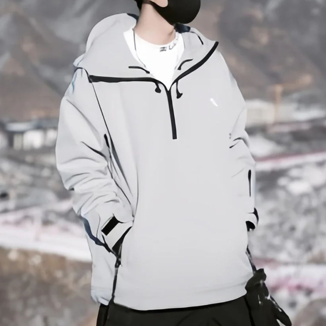 Parka ski grise et coupe-vent sur un homme sur fond de montagnes