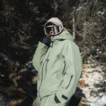 Parka ski verte imperméable à capuche pour femme sur une femme dans des bois