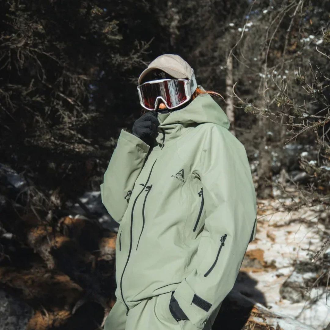 Parka ski verte imperméable à capuche pour femme sur une femme dans des bois